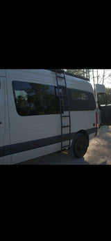 Explore in style with this rugged white rv rental camper van, featuring a ladder, roof rack, and off-road tires.