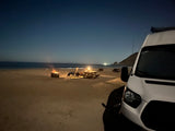 Enjoying a tranquil night beach camp with an rv rental. Campfire, chairs & picnic table by the ocean. Perfect stargazing.