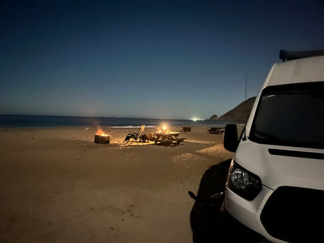Enjoying a tranquil night beach camp with an rv rental. Campfire, chairs & picnic table by the ocean. Perfect stargazing.