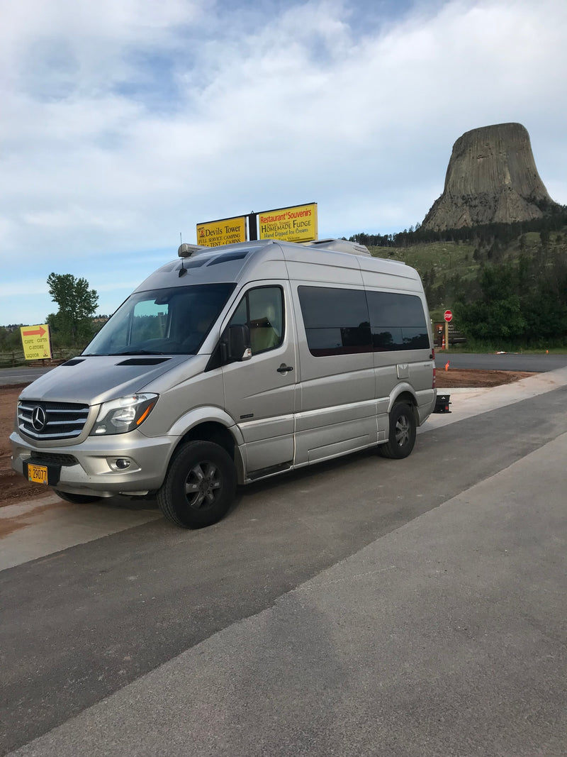  revealing a cozy interior. Mountains visible.|Silver Mercedes Sprinter RV rental van parked with Devils Tower in the background — photo 6