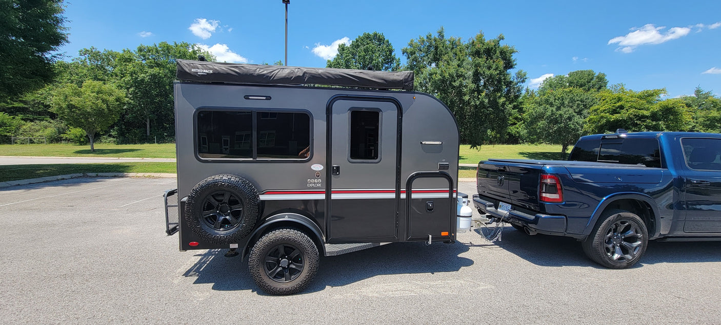 An RV rental journey begins: a compact gray travel trailer with off-road tires hitched to a blue pickup truck.