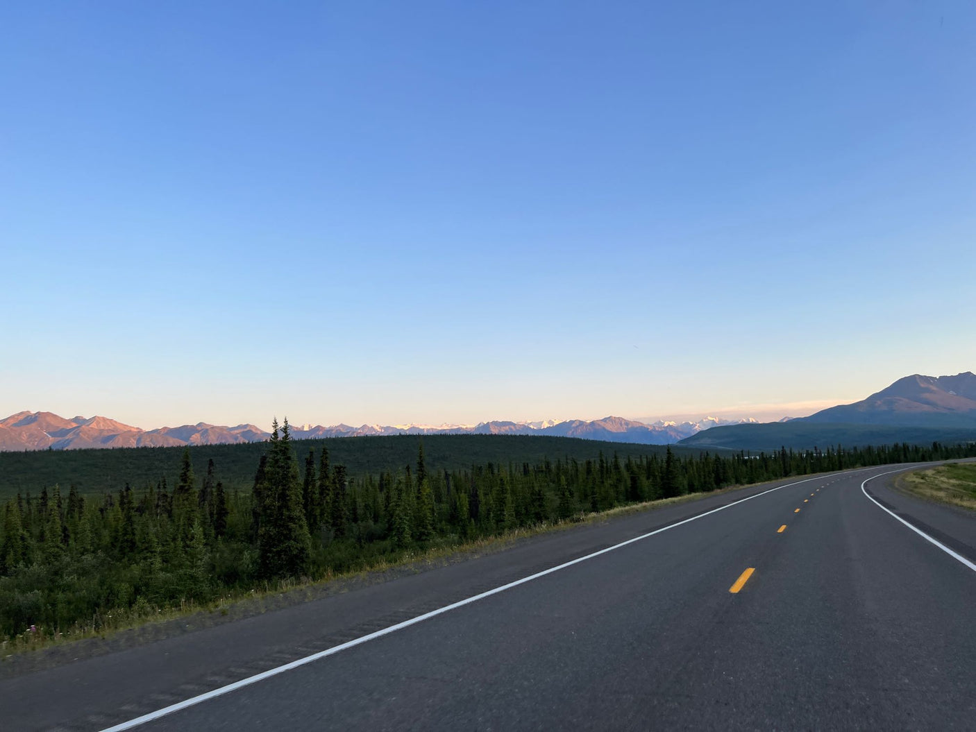 Scenic highway winds through forests toward distant mountains. Ideal for an RV rental road trip.