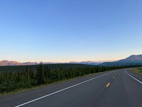 Scenic highway winds through forests toward distant mountains. Ideal for an RV rental road trip.