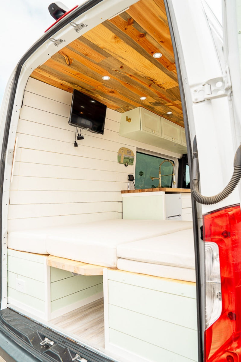  parked by a scenic coastline.|A cream-colored pot sits on a white portable electric stove on a wooden counter inside an RV rental — photo 12