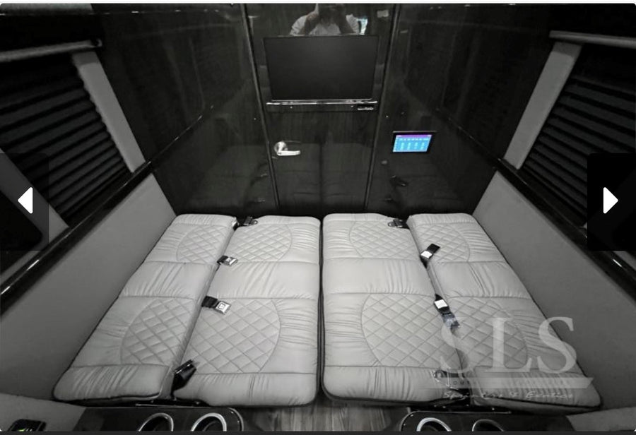 Luxury van RV rental interior: plush quilted beds/seats, TV, and control panel offer ultimate comfort for travel.