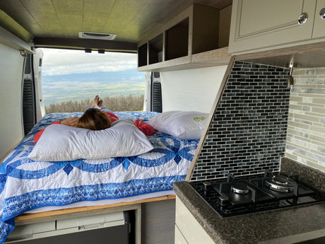 Enjoy the view from your RV rental! This customized van features a comfy bed with a scenic valley outlook and a functional kitchen.