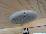 RV rental interior: View of the ceiling with a gray air vent/AC unit & light wood paneling featuring decorative grooves.
