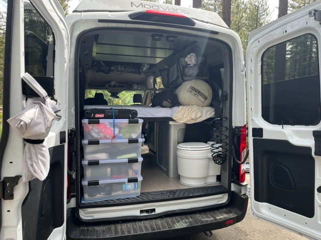 RV rental camper van's organized interior, showcasing efficient storage, portable toilet, and camping gear.