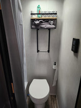 RV rental bathroom featuring a white toilet, shower with curtain, and a wall shelf above holding wipes, tissues, and towels.