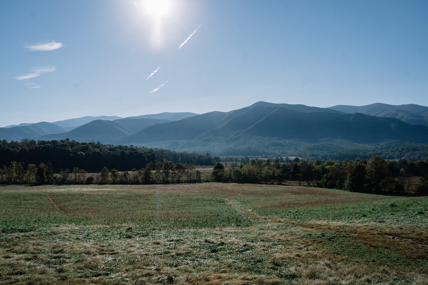 Scenic mountain views and a vast field await your RV rental adventure. Explore nature's beauty under a bright sky.