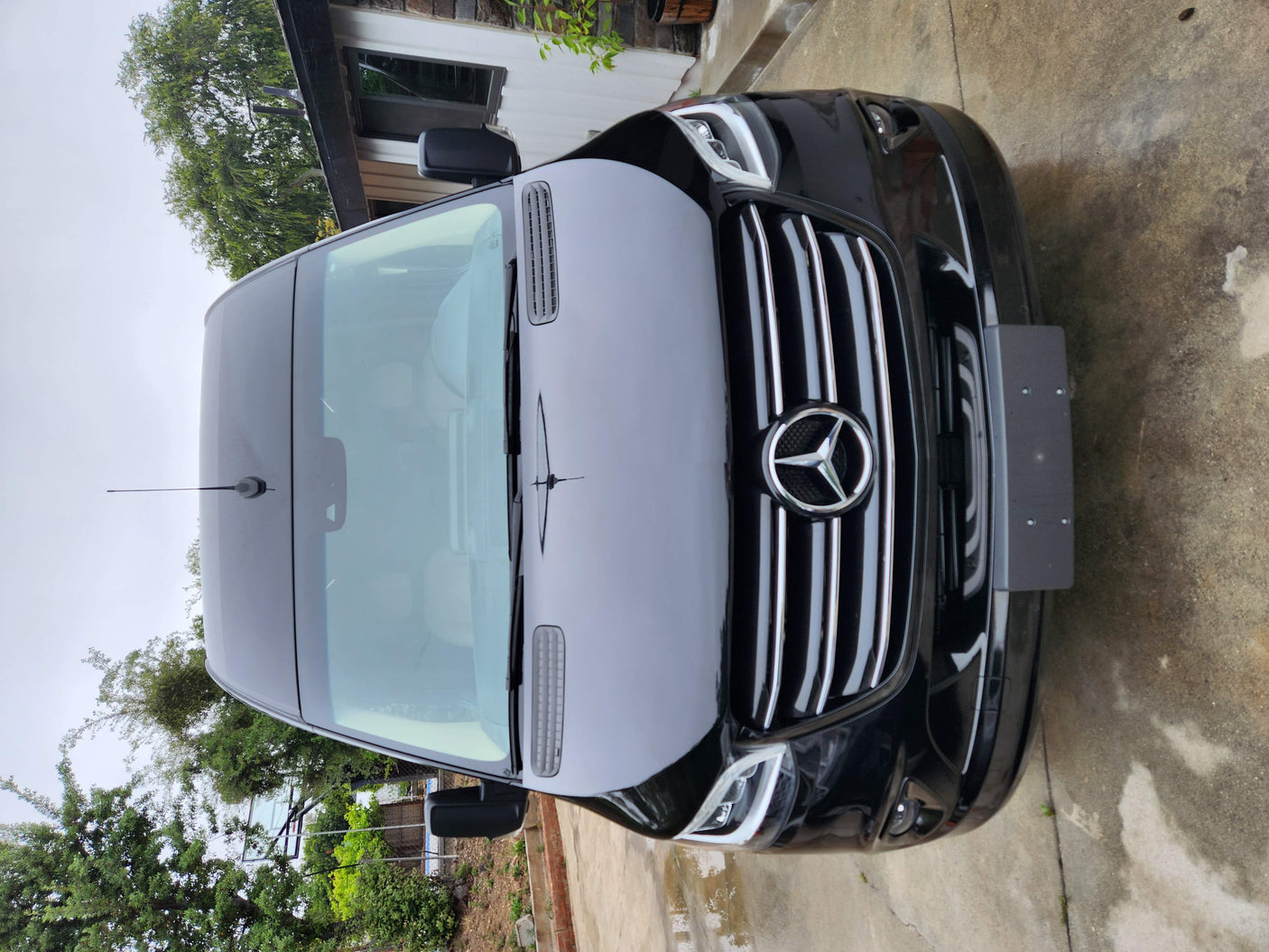 Black Mercedes-Benz Sprinter van, a common choice for an RV rental. Front view of the large passenger van parked.