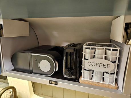 Compact kitchen setup in an **rv rental**, featuring a Keurig **coffee maker**, toaster, and a basket of **k-cups** with a "COFFEE" sign.