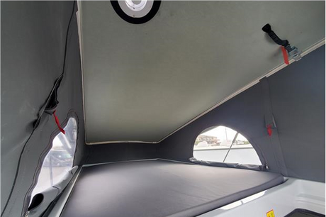 Explore your RV rental's pop-top sleeping area, featuring a comfortable bed, soft walls, and arched windows.