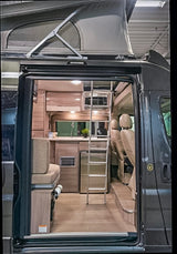 Explore this modern camper van RV rental interior! Features include a pop-top roof, kitchen, and ladder to an upper bed.