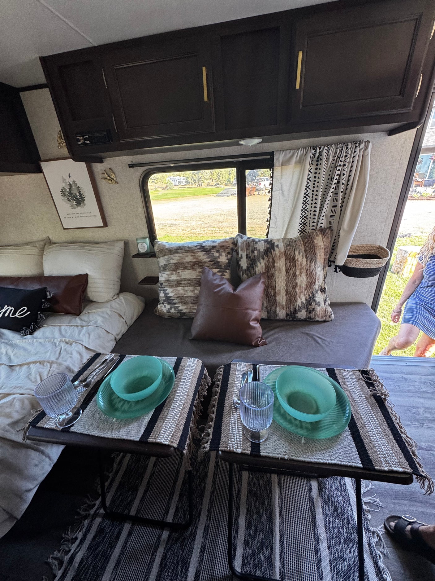 Inviting RV rental interior with a cozy bed, dining area set for two, and bohemian decor. Perfect for travel adventures.