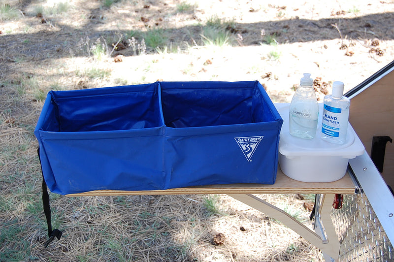 Blue Seattle Sports collapsible bin, Campsuds, and hand sanitizer on an RV rental outdoor table. Essential camping sanitation. — photo 8