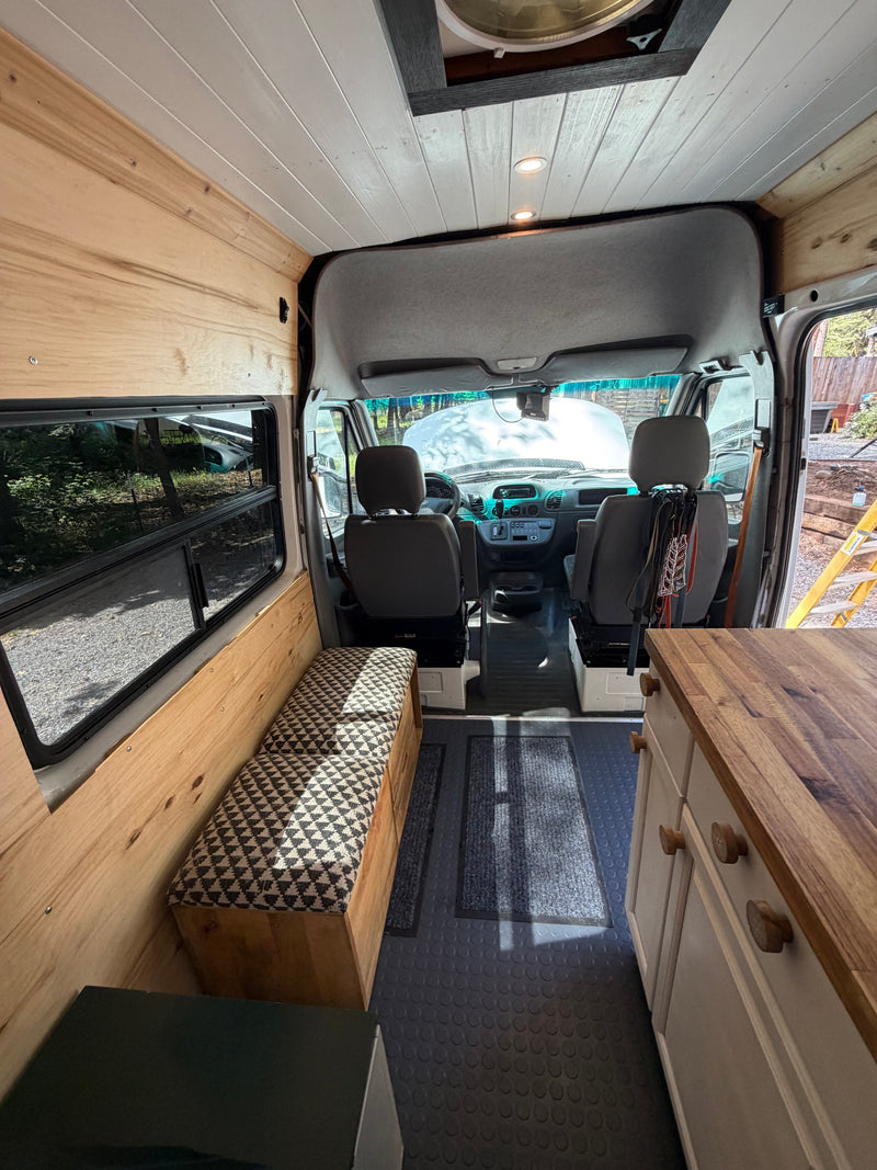 RV rental interior: wooden walls, white ceiling, comfy bench, kitchenette, and driver's cab visible. — photo 4