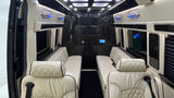 Luxury RV rental interior. View from front seats to the back, showing plush cream seating, dark glossy walls, and ambient blue lighting.