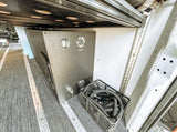 RV rental's fresh water system with honeycomb tank, fill port, gauge, spigot, and hose storage for camper van travel.