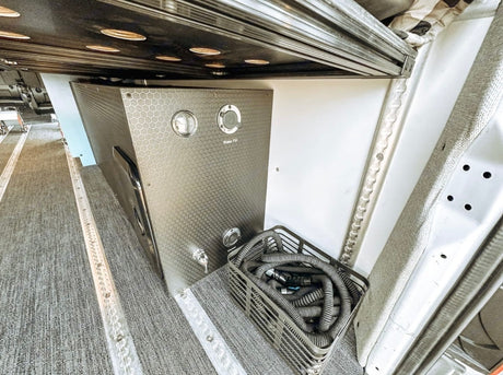 RV rental's fresh water system with honeycomb tank, fill port, gauge, spigot, and hose storage for camper van travel.