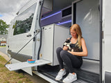 Enjoy a modern RV rental, featuring a woman and her cat enjoying the comfortable interior with an extendable outdoor table.