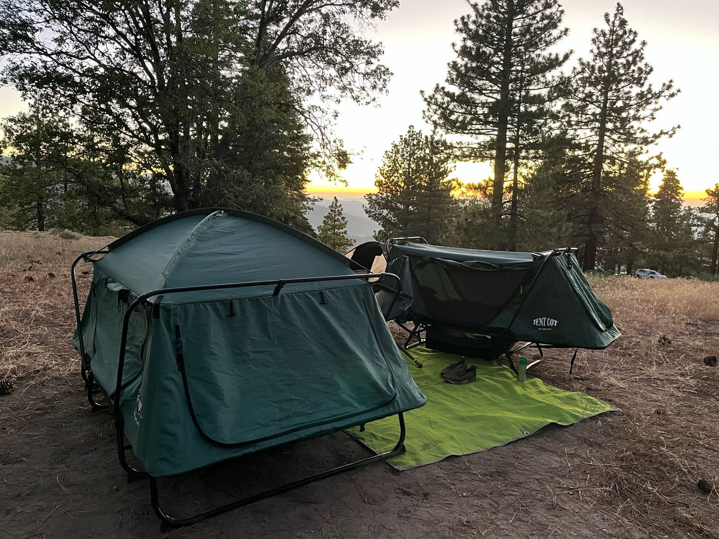 Two elevated tent cots at a sunset campsite. A unique camping experience, perfect as an alternative or addition to an RV rental.