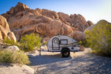 This cozy teardrop RV rental offers a desert escape, nestled among huge sun-drenched boulders and sparse greenery.