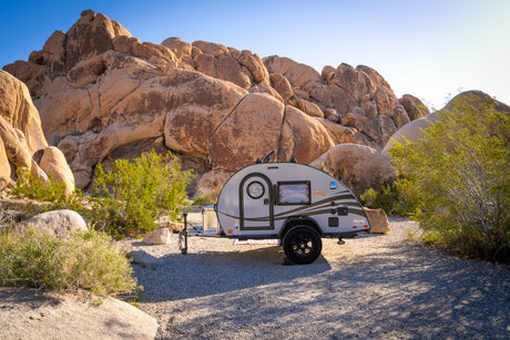 This cozy teardrop RV rental offers a desert escape, nestled among huge sun-drenched boulders and sparse greenery.