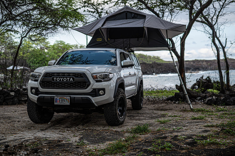 White Toyota Tacoma with a gray rooftop tent set up for coastal camping on Hawaii's lava rocks. Your adventure RV rental. — photo 5