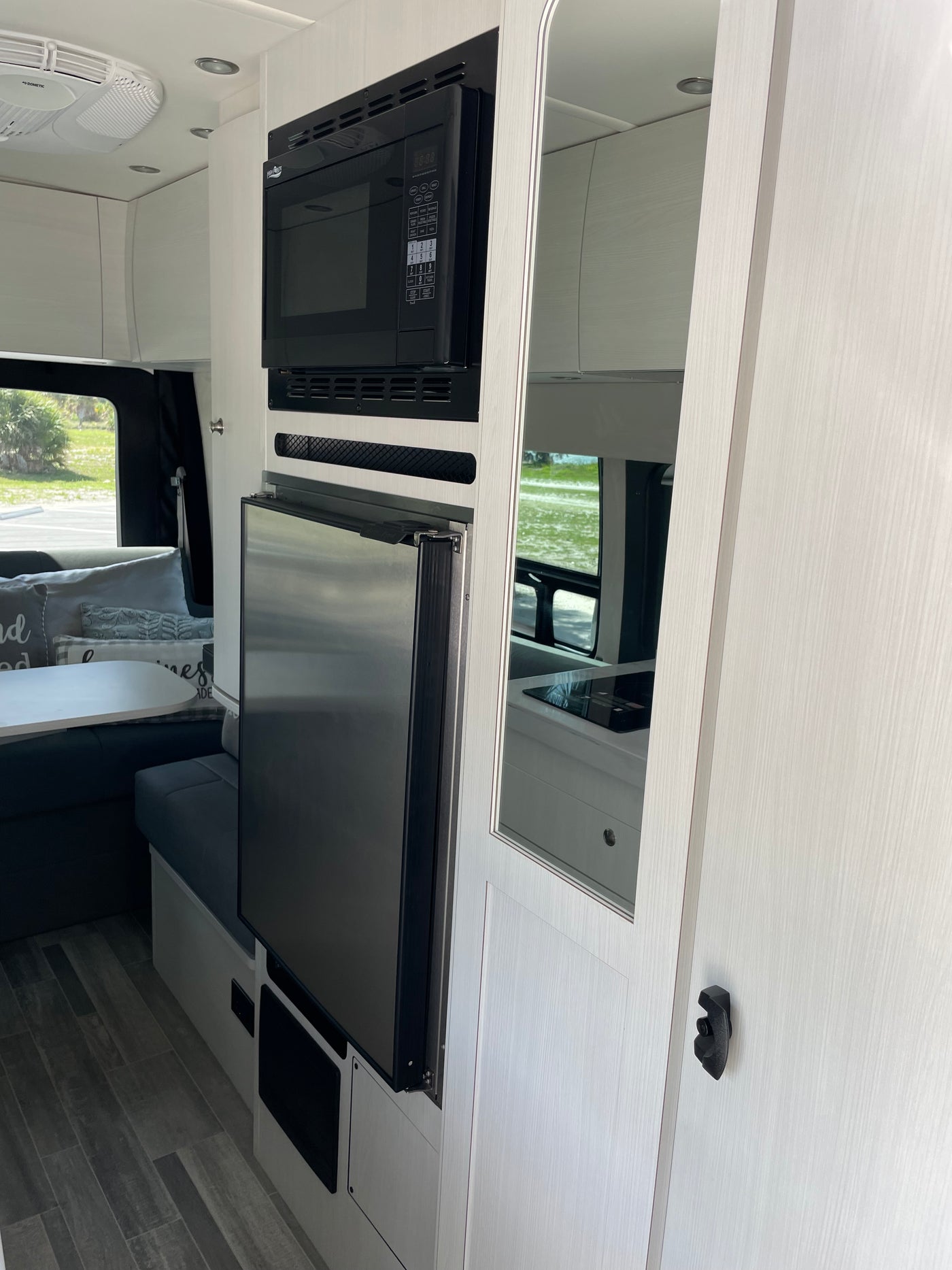 Modern rv rental interior with microwave, refrigerator, white cabinets, and mirrored panels. — photo 6