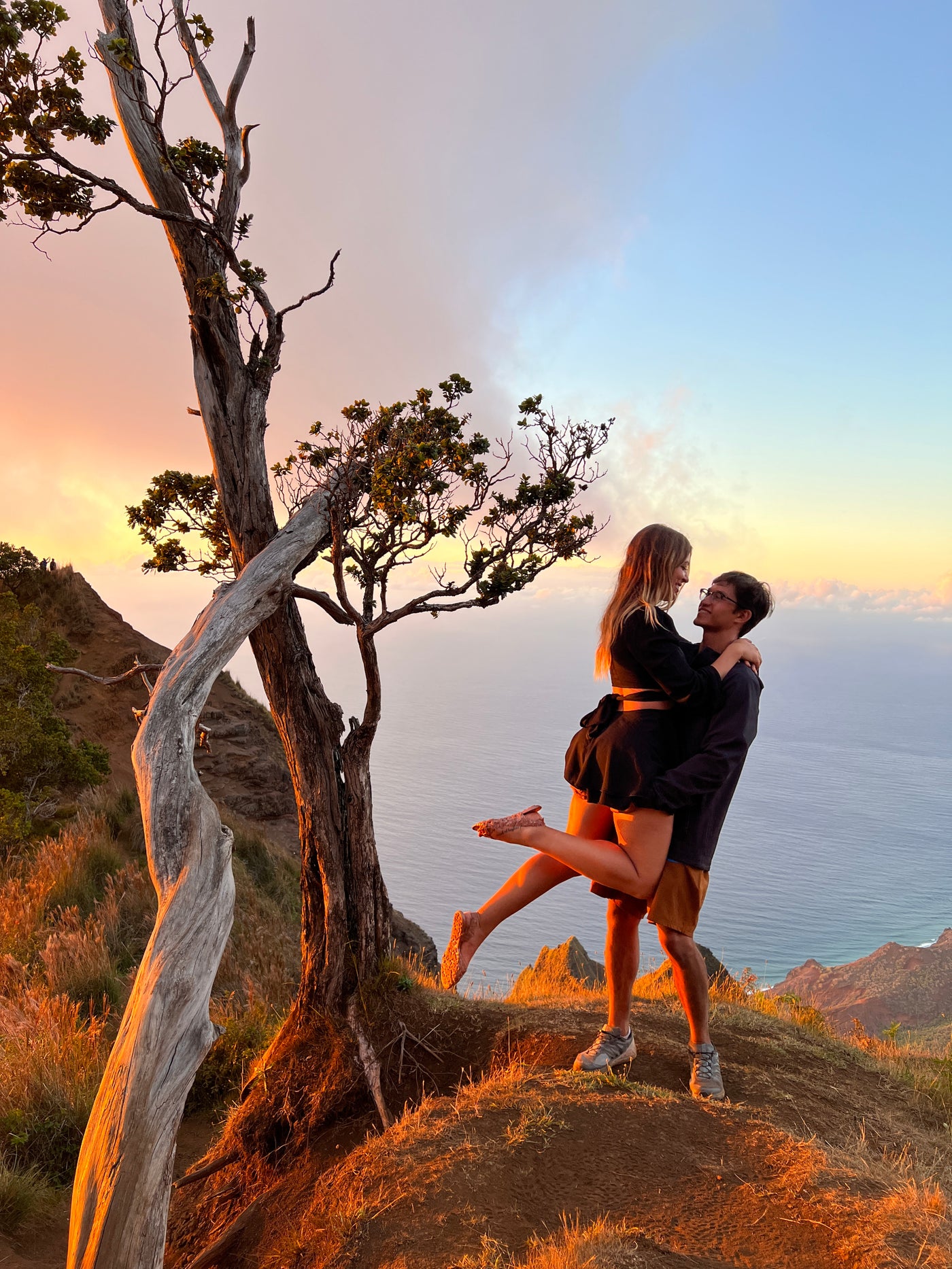 A loving couple embraces on a golden-lit mountain overlooking the ocean at sunset. An RV rental makes trips like this possible! — photo 3