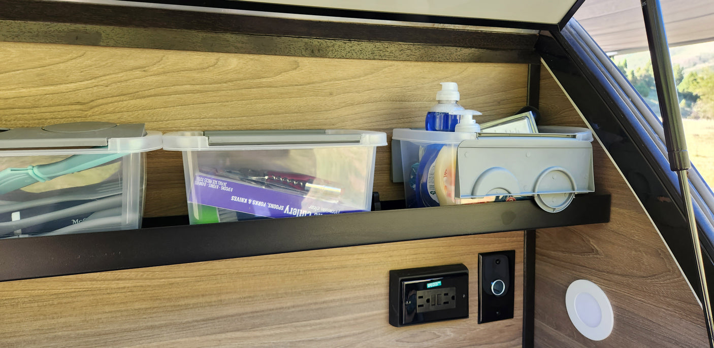 RV rental interior showing smart storage with kitchen utensils & soap, power outlets, and a view outside.