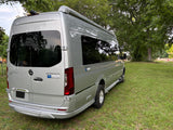 This silver Airstream Interstate RV rental, a Mercedes Sprinter camper van, is parked on lush green grass outdoors.