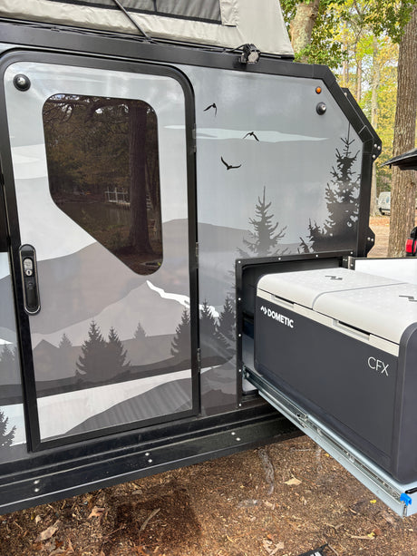 Modern rv rental with Dometic CFX portable fridge on a slide-out, showcasing mountain graphics. Ready for outdoor adventure.