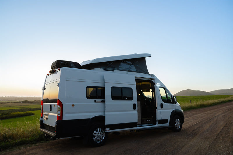  and a person on a dirt road at sunset.|This white RV rental van — photo 4