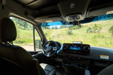 Modern RV rental interior with sleek dashboard and serene green landscape view, perfect for outdoor adventures.
