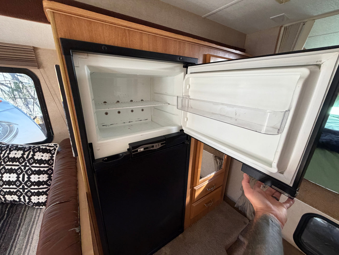 Empty RV rental refrigerator with shelves and door storage, ready for your trip. A separate freezer section is below.