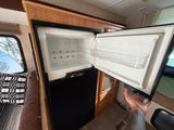Empty RV rental refrigerator with shelves and door storage, ready for your trip. A separate freezer section is below.