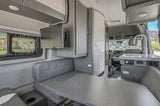 Inside a sleek rv rental: dinette, kitchen sink, TV, and scenic window view, ready for your next adventure.