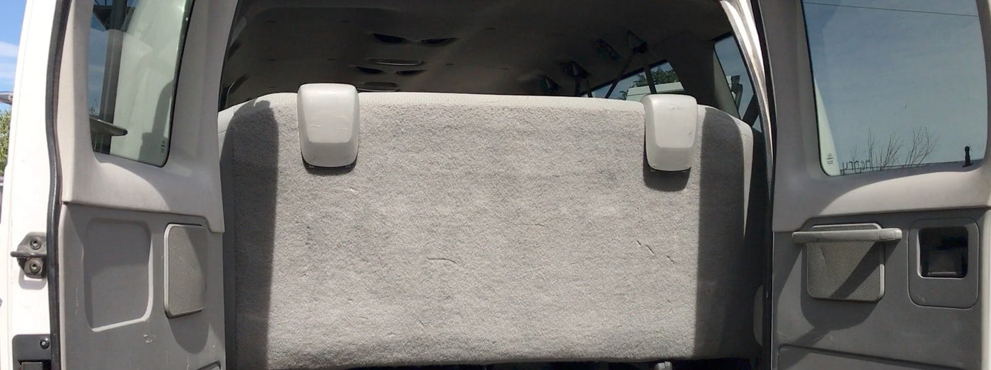  parked under a canopy with other rental vehicles.|RV rental rear interior: open doors reveal a grey bench seat — photo 3