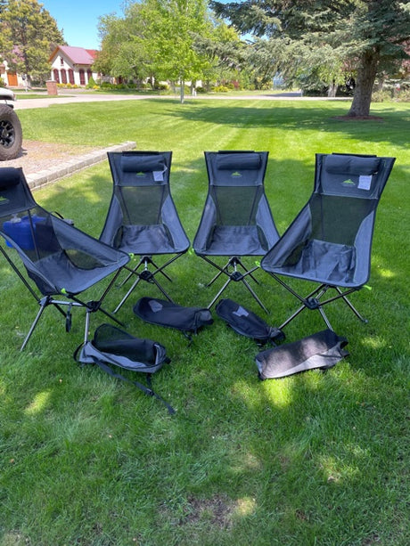 Four compact chairs & bags laid on green grass, ready for outdoor relaxation. Perfect for your RV rental adventure!