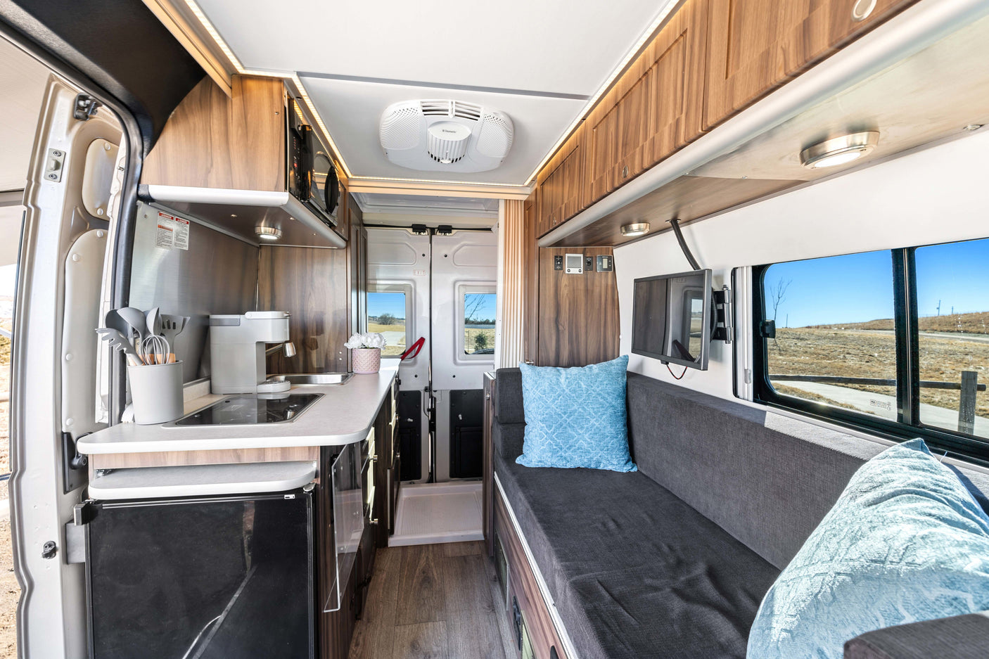 Modern rv rental van conversion interior: compact kitchen, lounge with TV, and ample storage for comfortable trips.
