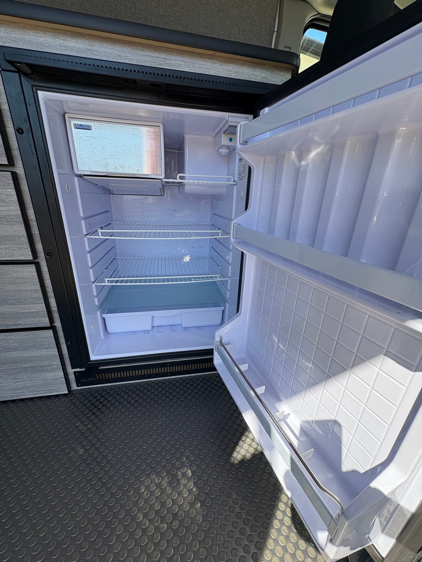 New RV rental fridge, spotless and ready for groceries, features freezer and adjustable shelves. — photo 11