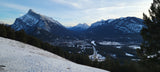 From a snowy slope, behold Banff, Alberta's winter splendor with towering Rockies & valley town. Ideal for an RV rental adventure.