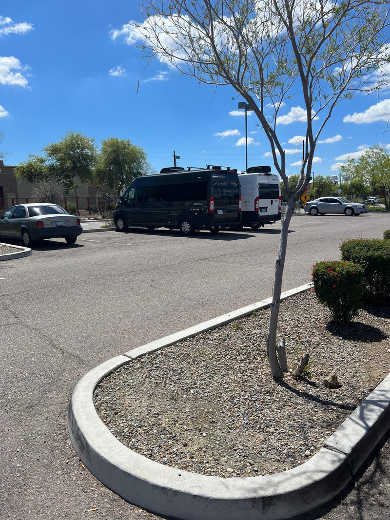 A sunny parking lot features a dark Jayco Swift and a white Solis camper van, indicating RV rental services, alongside other vehicles. — photo 9