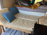 This RV rental shows a cozy, multi-functional interior with a ribbed sofa-bed, elevated sleeping area, and small kitchen space.