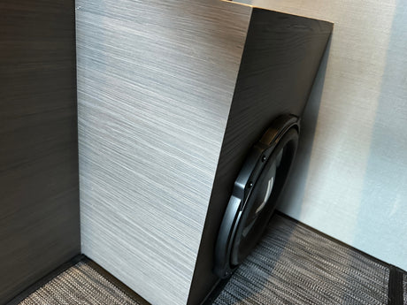 Modern **RV rental** interior with a large subwoofer neatly integrated into sleek, two-toned textured cabinetry.