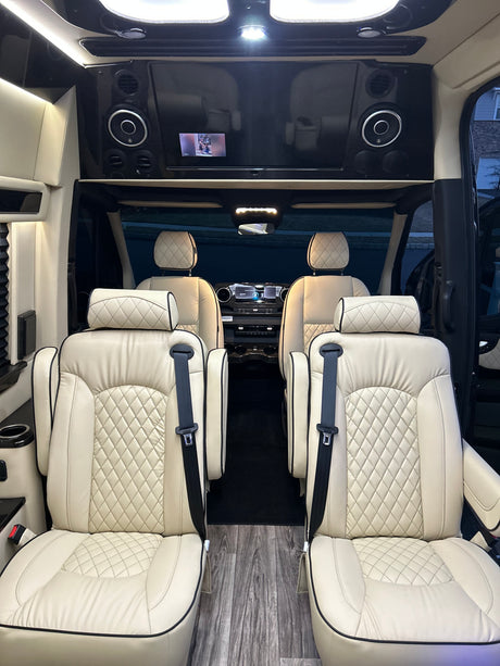 Luxury RV rental interior with plush cream seating and entertainment displays for comfortable travel.