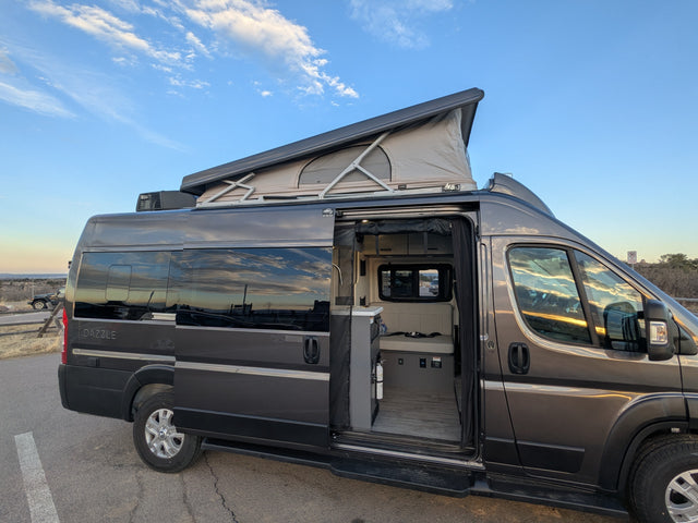 Gray pop-top camper van, perfect for your next RV rental adventure. Interior visible through open side door.