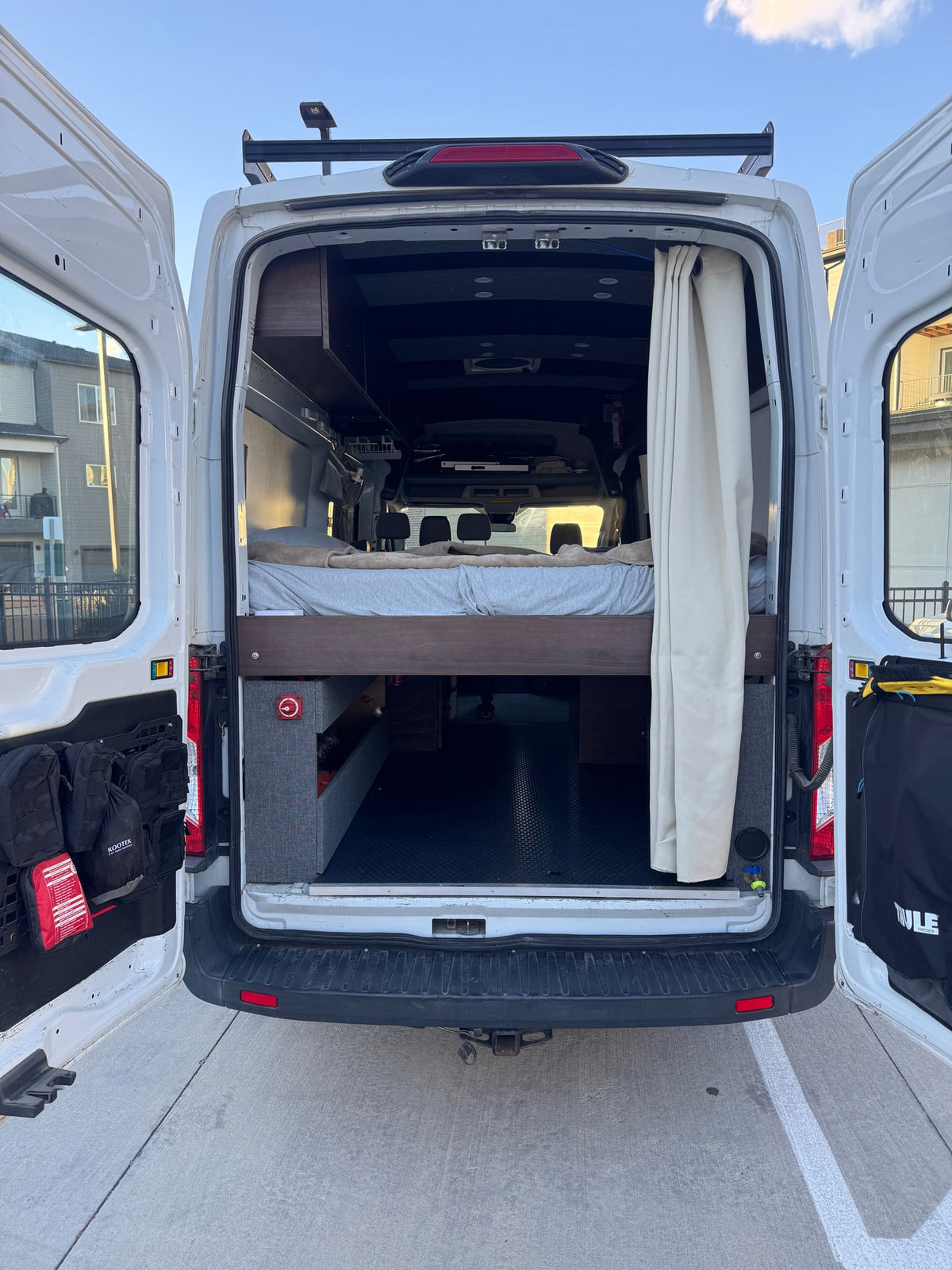  and carpeted overhead storage. Scenic view out front.|RV rental camper van interior. Open door shows bed — photo 12